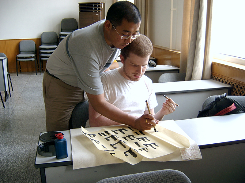 Hua laoshi assists a student practice writing Chinese characters