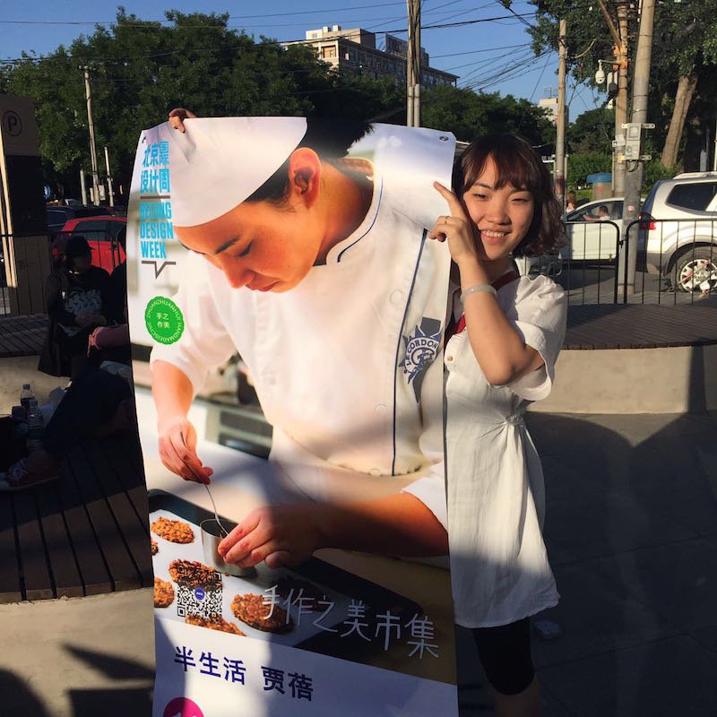 Jia Bei, an elite trained pastry chef, hoists a poster for her La Vie Simple bakery