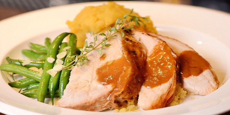 Turkey served with mashed sweet potato, cornbread stuffing, butter sautéed green beans