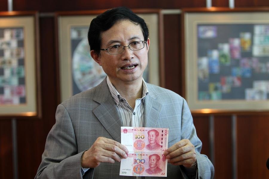 Shao Guowei, chief technology officer of China Banknote Printing and Minting Corporation holds an old note and a new one