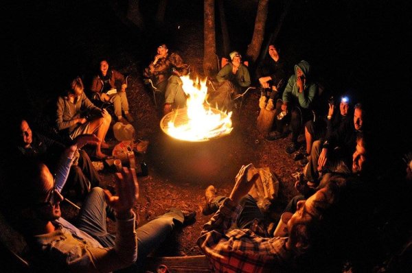 Some people around a campfire telling stories or not really listening but too cold to go back to their tent.